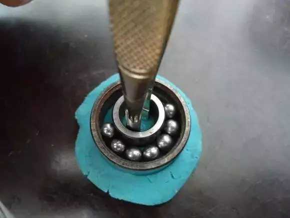 用鑷子或別的相近的物體越過內(nèi)圈，同時(shí)向滾珠的方向用力頂住